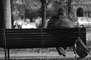 Homeless man sat on a bench in the park