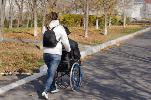 Carer pushing older person in a wheelchair